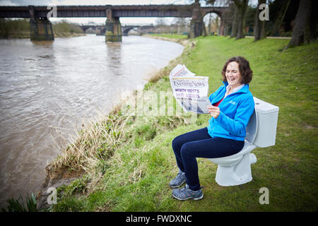 Seduto su un wc leggendo il giornale vasino loo orinatoio seduta utilizzando acque luride Foto Stock