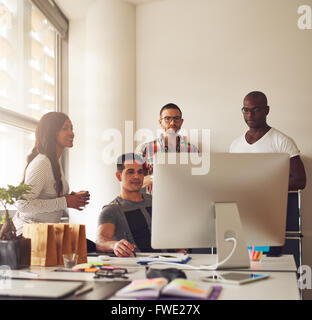 Gruppo diversificato di nero, Ispanico e Caucasico adulti giovani imprenditori insieme al piccolo ufficio con grandi e luminose win Foto Stock