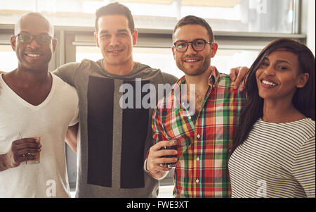 Il gruppo di quattro per il nero, caucasiche e ispanica adulto felice amici indossando un abbigliamento informale e tenendo le bevande mentre abbracciando ogni Foto Stock