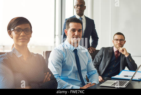 Sorridente fiducioso multirazziale business team seduti a un tavolo in una sala conferenze in ufficio rendendo le decisioni manageriali Foto Stock