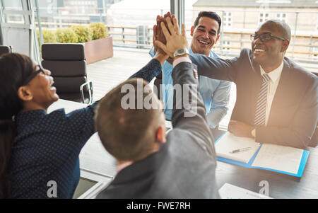 Esultante team di multirazziale giovani professionisti esultanza e congratulandomi con ogni altro dando un alto cinque gesto Foto Stock