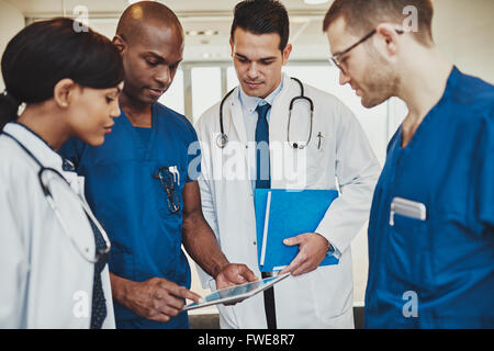 Team di medici e multirazziale in ospedale a discutere di un paziente, i medici utilizzano tablet Foto Stock