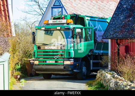 Kivik, Svezia - Aprile 1, 2016: un verde Scania 230 camion della spazzatura stand in un accoppiamento a tenuta fra le case mentre la raccolta di famiglia g Foto Stock