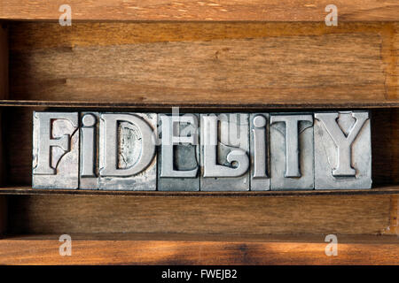 Parola di fedeltà fatta da metallico tipo di stampa in rilievo sul vassoio in legno Foto Stock
