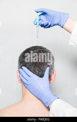 Medico aesthetician rende acido ialuronico iniezioni di bellezza sulla fronte del paziente di sesso maschile in un cappuccio di medici e t-shirt bianco Foto Stock