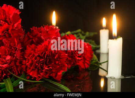 Le candele e i fiori di colore rosso su nero di una lastra di marmo Foto Stock