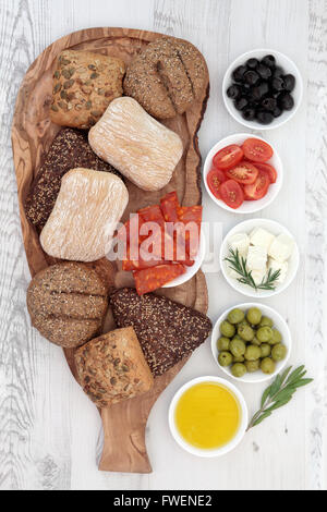 Picnic food con salame chorizio, il formaggio feta, le olive, pomodori, olio di erba e foglie ciuffi con pane rustico rotoli . Foto Stock