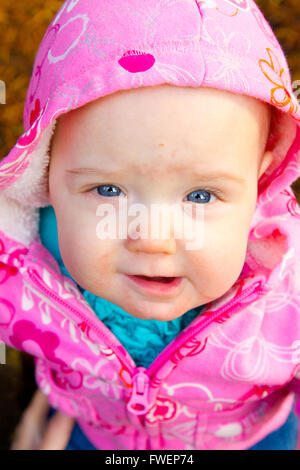 Una giovane ragazza infantile in rosa è fotografato all'aperto per questo bambino ritratto. Foto Stock