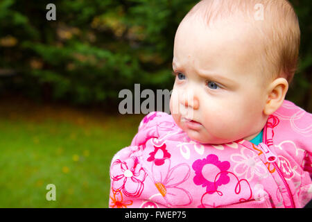 Una giovane ragazza infantile in rosa è fotografato all'aperto per questo bambino ritratto. Foto Stock