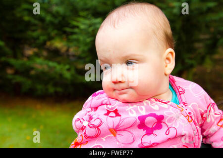 Una giovane ragazza infantile in rosa è fotografato all'aperto per questo bambino ritratto. Foto Stock