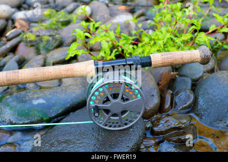 Un fly canna da pesca e Mulinello sedersi su qualche roccia di fiume sul bordo del fiume Willamette in Oregon. Foto Stock