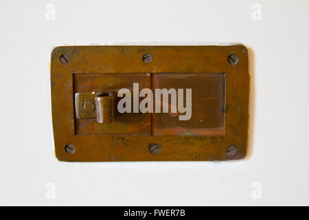 Un foro di peep in una porta bianca è realizzato al di fuori di un vintage bronzo antico. Foto Stock