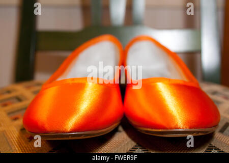 Arancione scarpe o appartamenti sono impostate su una sedia prima di una sposa li indossa per il suo matrimonio. Foto Stock