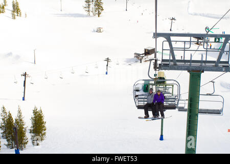 Un paio di persone ride sci seggiovia fino alla montagna insieme mentre è seduto vicino a ogni altro avente un momento divertente durante Foto Stock