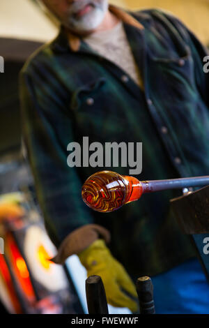 Un talento molto glassblower è di formatura e lavorazione di vetro in un studio per la fabbricazione del vetro. Egli è la creazione di un vaso scanalato da questo pi Foto Stock