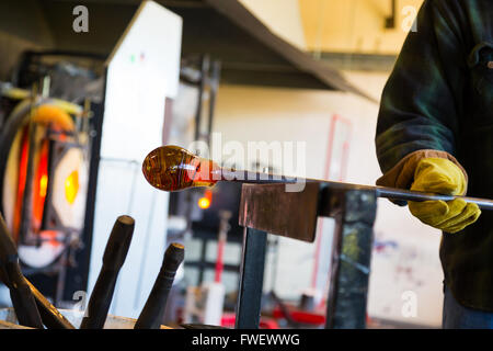 Un talento molto glassblower è di formatura e lavorazione di vetro in un studio per la fabbricazione del vetro. Egli è la creazione di un vaso scanalato da questo pi Foto Stock