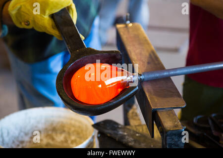 Un talento molto glassblower è di formatura e lavorazione di vetro in un studio per la fabbricazione del vetro. Egli è la creazione di un vaso scanalato da questo pi Foto Stock