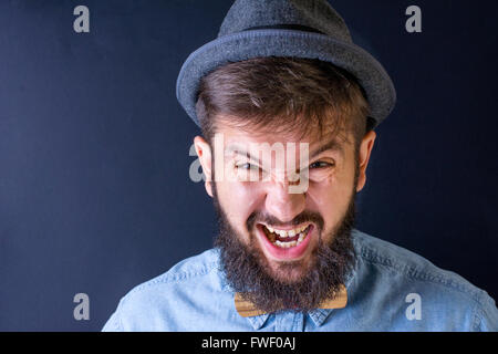 Arrabbiato uomo barbuto yealing in una maglietta blu Foto Stock