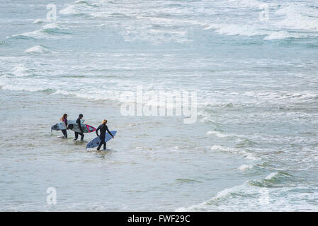 Tre i surfisti a piedi per il mare a Fistral Beach in Newquay Cornwall, Foto Stock