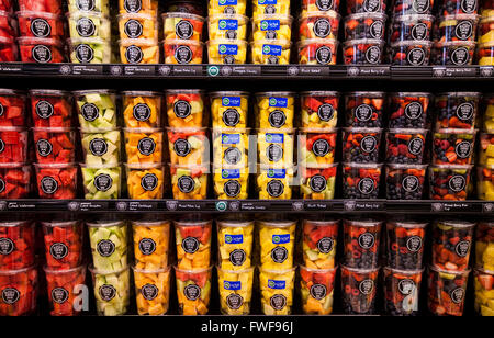 Contenitori di plastica di pronto a mangiare frutta tritato vengono impilati in righe in un contenitore refrigerato in un negozio di alimentari. Foto Stock