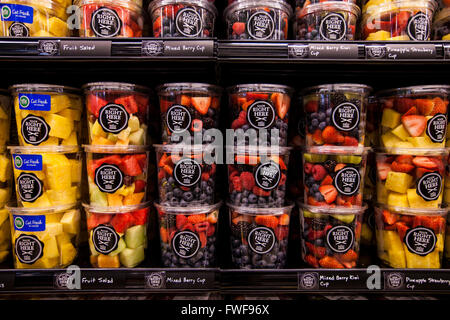 Contenitori di plastica di pronto a mangiare frutta tritato vengono impilati in righe in un contenitore refrigerato in un negozio di alimentari. Foto Stock