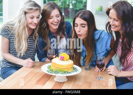 Donna soffiando le candeline sulla sua torta di compleanno con i suoi amici Foto Stock