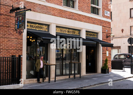 Un uomo con un drink al di fuori dei posti blu pub di Londra, Regno Unito. Foto Stock