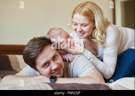 Mamma e papà a giocare con il suo Figlio bambino sul letto. Happy family concept Foto Stock