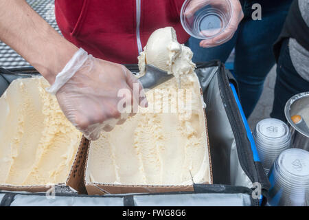 Un lavoratore palline di gelato alla vaniglia in una tazza in corrispondenza di un evento a New York il giovedì 31 marzo, 2016. A causa della debolezza del baccello di vaniglia raccolti in Madagascar i prezzi di gelato alla vaniglia e qualsiasi altro prodotto utilizzando le spice sono attesi in aumento quest'estate. (© Richard B. Levine) Foto Stock