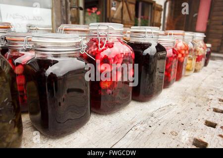 Vibrante e clored testefuly cercando frutta sciroppata e vasi di marmellata sul tavolo Foto Stock