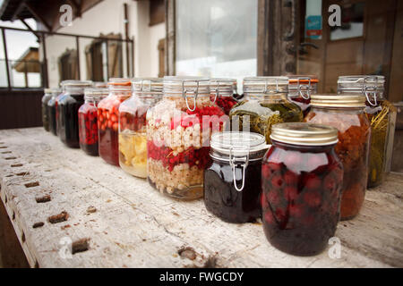 Vibrante e clored testefuly cercando frutta sciroppata e vasi di marmellata sul tavolo Foto Stock