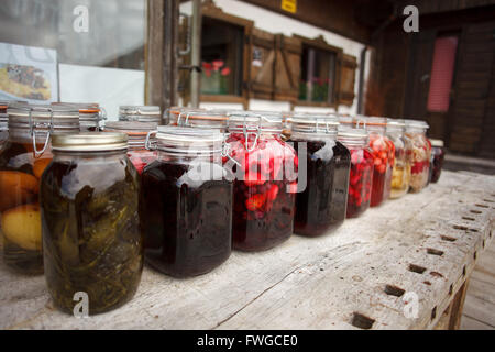 Vibrante e clored testefuly cercando frutta sciroppata e vasi di marmellata sul tavolo Foto Stock