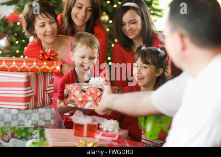 Un gruppo di persone e di genitori e bambini, famiglia scambiando presenta la mattina di Natale. Foto Stock