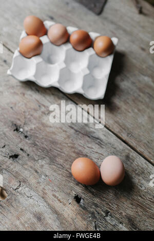 Fresco di gallina uova in una scatola e su un tavolo di legno. Foto Stock