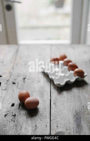 Fresco di gallina uova in una scatola e su un tavolo di legno. Foto Stock