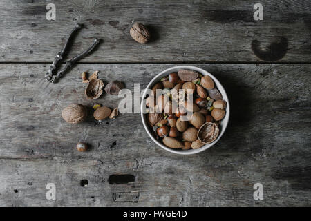 Una ciotola di dadi misti, conchiglie e uno schiaccianoci su un tavolo. Foto Stock