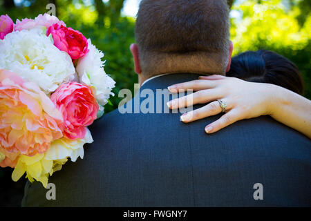 La sposa mette la mano sulla spalla del groom danzando per creare questa immagine che si concentra sul suo wedding band ring. Foto Stock