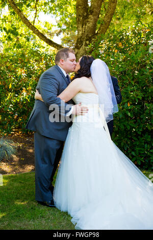 La sposa e lo sposo condividono il loro primo bacio come una coppia di sposi e di avere un momento insieme durante i loro voti matrimoniali cerimonia presso un Foto Stock