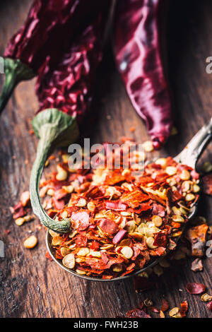Peperoncino. Il peperoncino. Più secchi peperoncino frantumato e peperoni su un vecchio cucchiaio versato intorno a. Ingredienti messicani - cui Foto Stock
