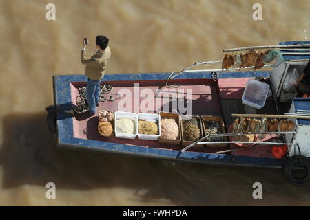 Uomo al cellulare, in piedi sul ponte di sampan cinesi (mercato barca), il fiume Yangtze, Cina Foto Stock