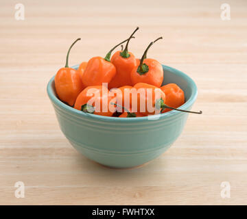 Vista laterale di una ciotola di orange habanero peperoni in una cucina in legno sul bancone. Foto Stock