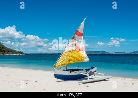 Outrigger malgascio piroga con Coloratissime vele di fortuna sulla spiaggia bianca Foto Stock
