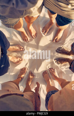 Top Visualizza immagine del variegato gruppo di amici a piedi nudi in cerchio sulla spiaggia sabbiosa. Piedi di giovani in piedi in cerchio Foto Stock