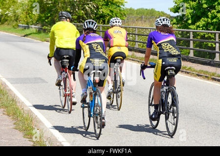 Gruppo di quattro ciclista da Cycling Club su una tranquilla strada di campagna sul ponte indossando caschi e colorato abbigliamento sportivo lycra Essex Inghilterra UK Foto Stock