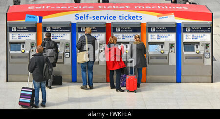 Biglietti self-service per la vista posteriore dei passeggeri del treno e dei bagagli in attesa presso l'atrio principale delle macchine, London Waterloo, stazione ferroviaria, Inghilterra, Regno Unito Foto Stock