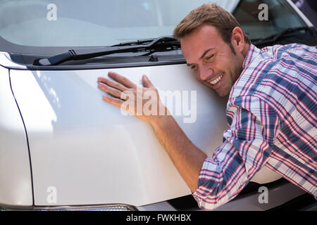 Giovane uomo abbracciando la sua auto Foto Stock