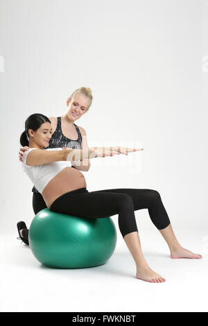 Donna incinta facendo esercizio di fitness con personal trainer Foto Stock
