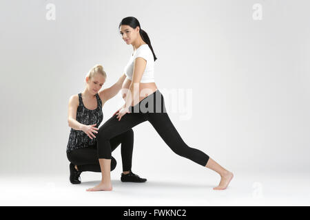 Donna incinta facendo esercizio di fitness con personal trainer Foto Stock