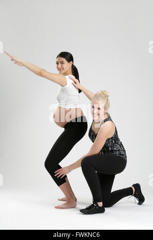 Donna incinta facendo esercizio di fitness con personal trainer Foto Stock