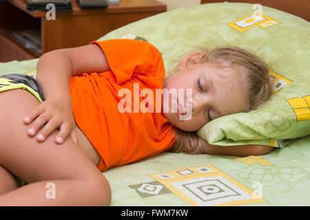 Piccola ragazza dorme sul suo fianco nella sua mano sotto il cuscino del letto Foto Stock